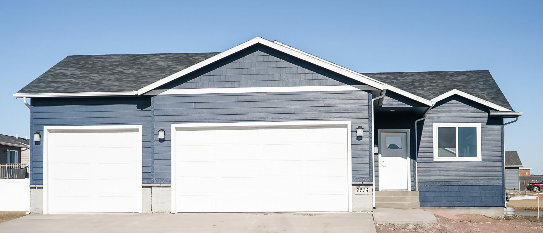 Single Family with front window next to a White Front Door and Three Stall Garage