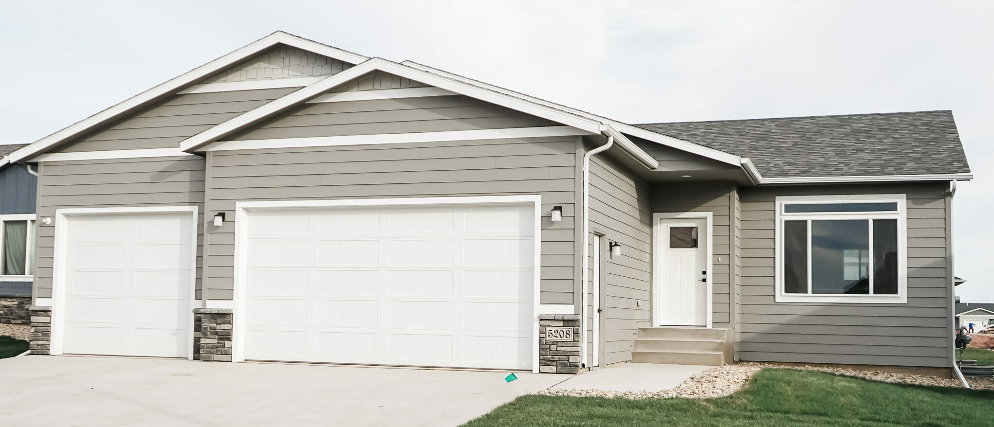 Single Family Home with large front window, white door and three stall garage