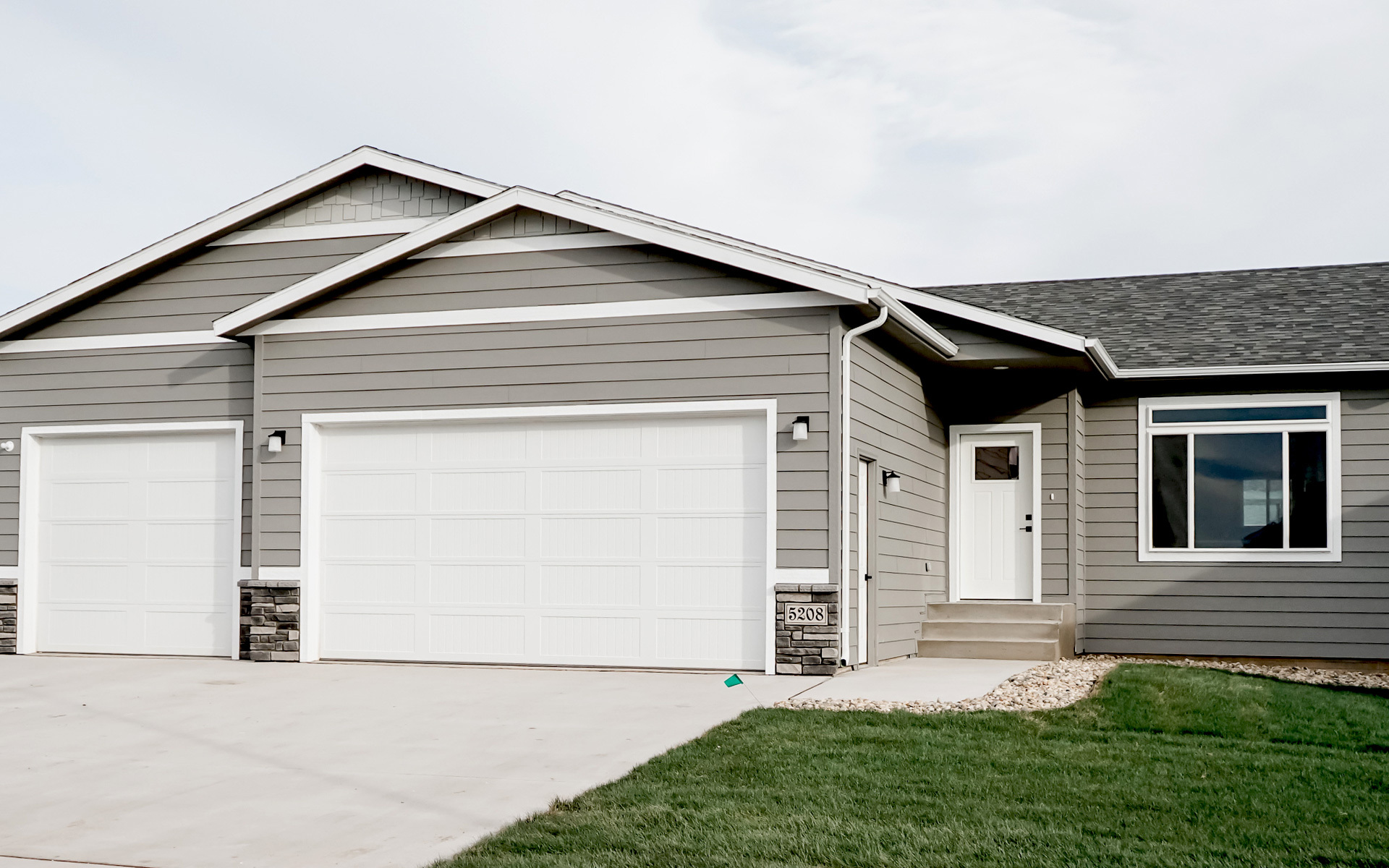 A new construction home with grey exterior and a three car garage.