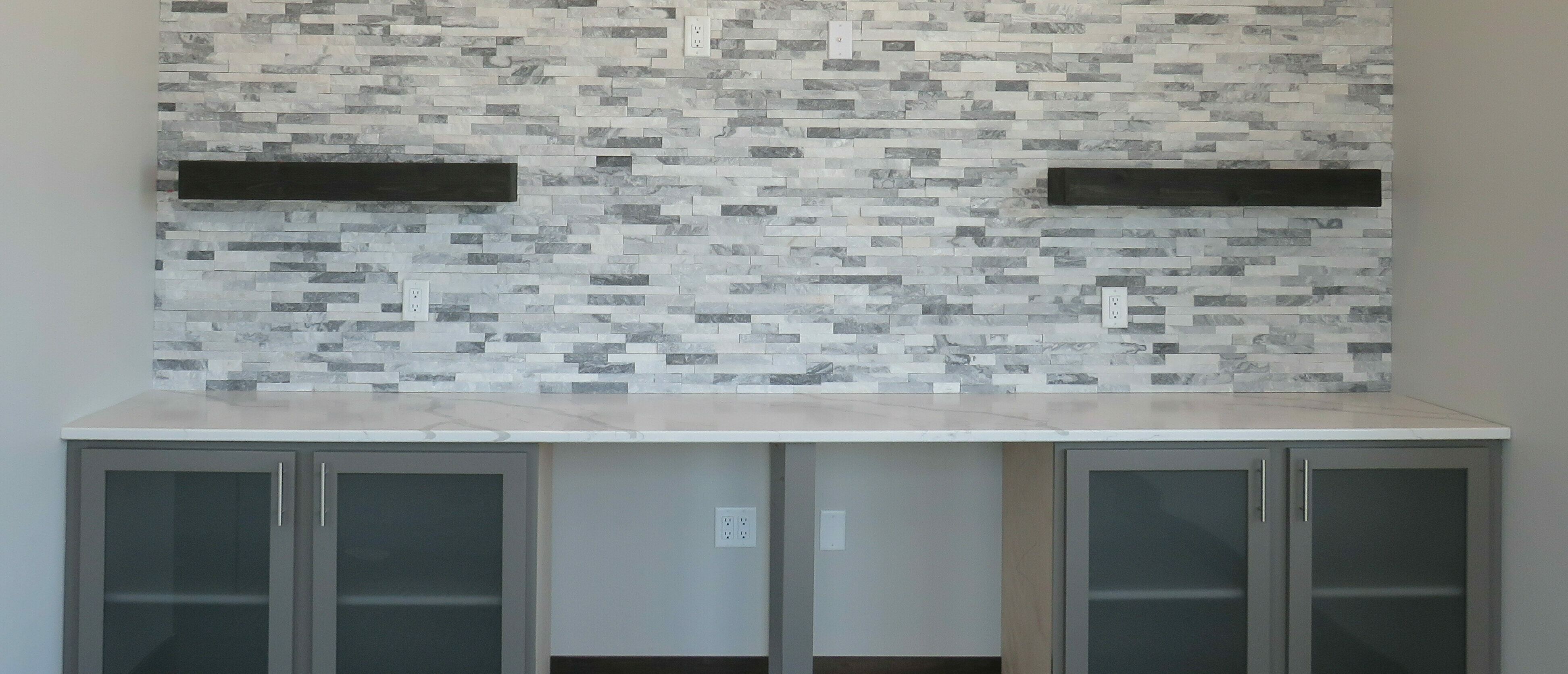 Office Conference Room Grey Storage Cabinets with stone accent wall with two floatings shelves above a white quartz countertops