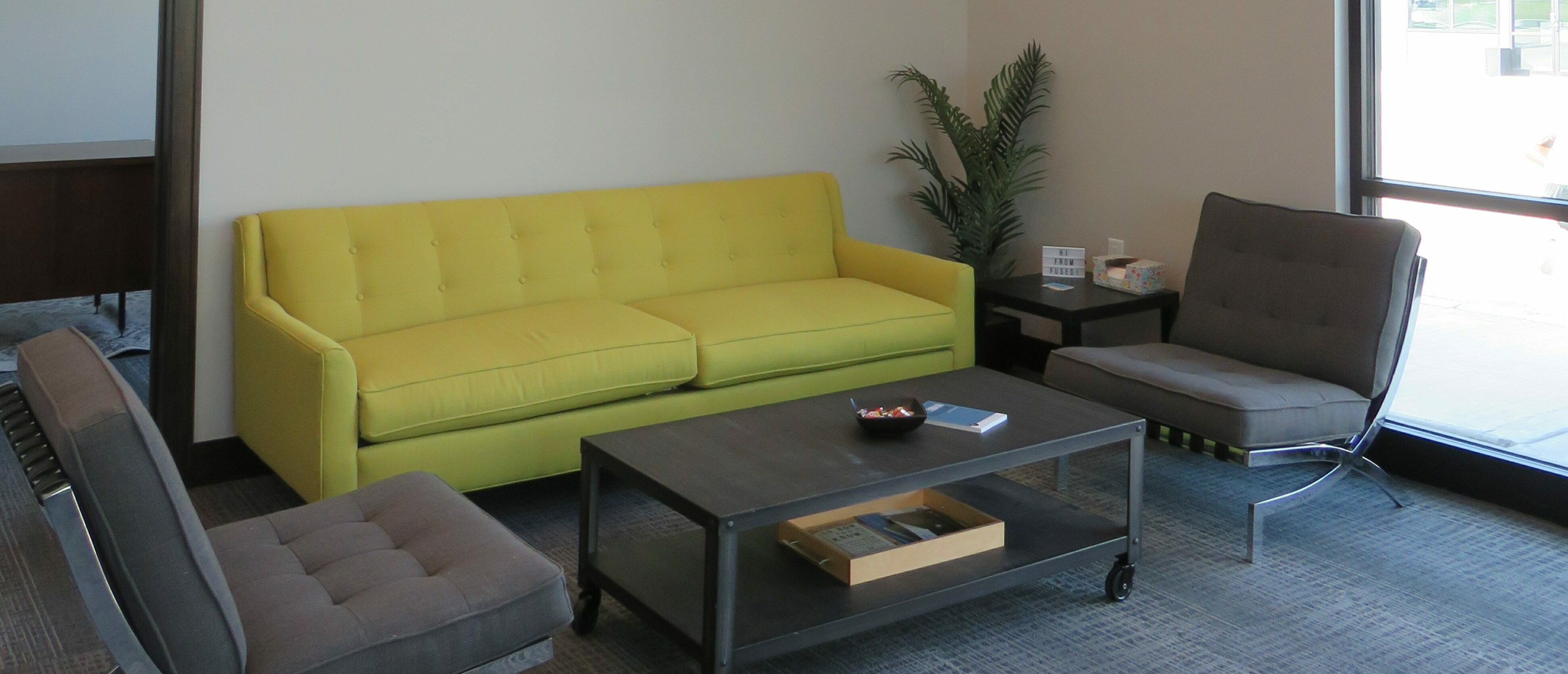 Office Welcome Area with green couch and two modern chairs facing a coffee table
